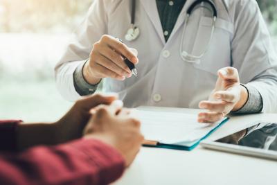 Pictured: A doctor with clipboard consulting with a patient 