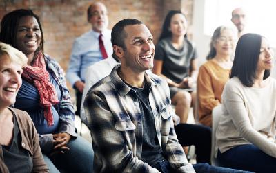 Pictured: A small audience smiling at an unseen presenter 