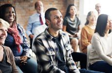 Pictured: A small audience smiling at an unseen presenter 