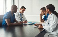 Pictured: A small group of healthcare workers collaborating at a conference room table