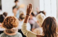 Pictured: A woman in a small audience raising her hand