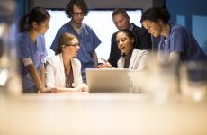 Group of clinicians around a laptop.