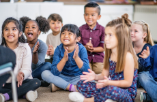 Photo of smiling young students looking at teacher