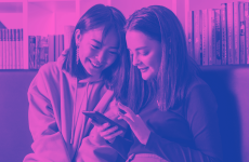 Two smiling teens looking at phone