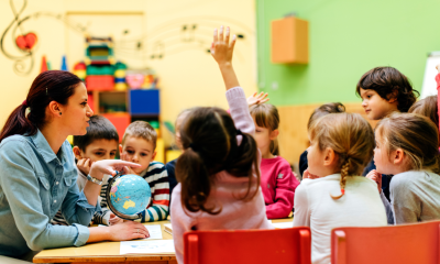 Photo of a young student raising her hand during a lesson