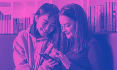 Two smiling teens looking at phone