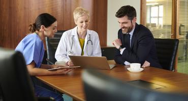 Doctor's sitting around a table looking at a computer 