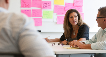 Three colleagues speaking at a table