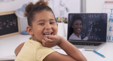 Smiling child learning on laptop