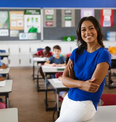 Smiling teacher in front of classroom of young students