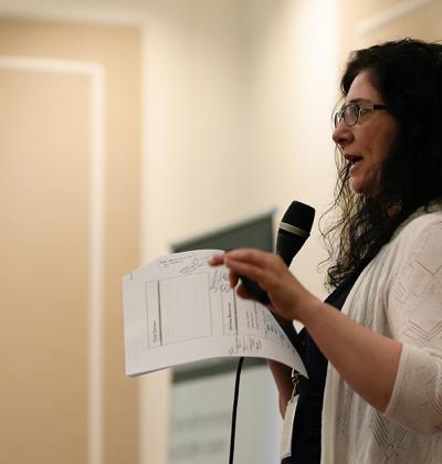 Woman standing at the front of the room holding a microphone