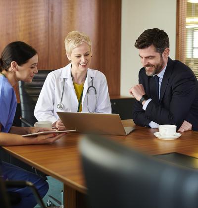Doctor's sitting around a table looking at a computer 