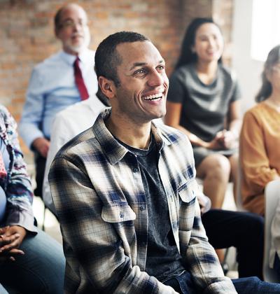 Pictured: A small audience smiling at an unseen presenter 