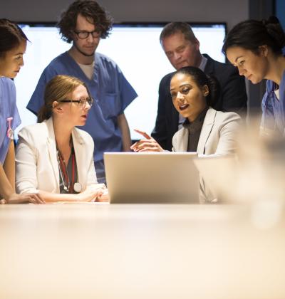 Group of clinicians around a laptop.