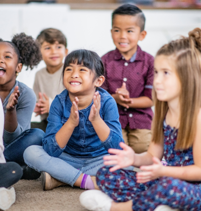 Photo of smiling young students looking at teacher