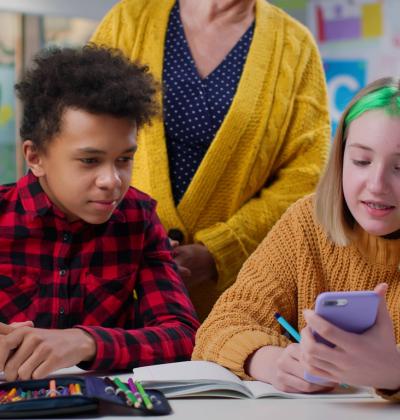 Teacher notice teen students using smartphone during lesson in class stock photo