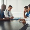 Pictured: A small group of medical staff collaborating at a conference room table